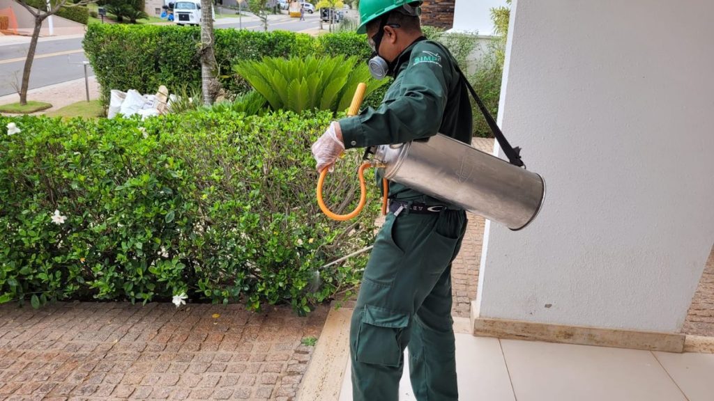 Técnico aplicando controle preventivo em área residencial.